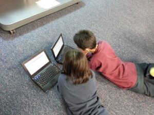 two children learning on laptops
